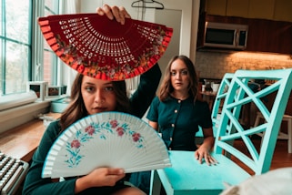 woman in black long sleeve shirt holding white and red floral hand fan
