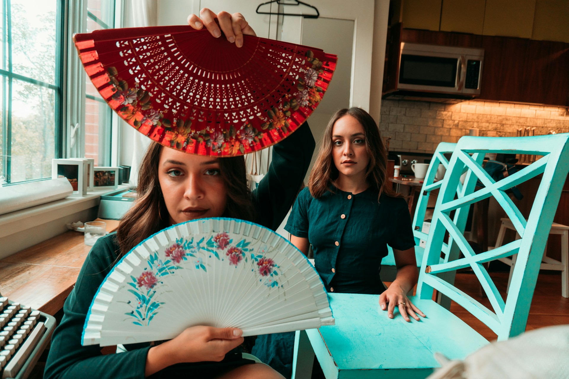 woman in black long sleeve shirt holding white and red floral hand fan