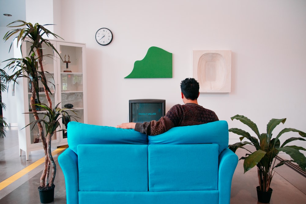 man in black and red jacket sitting on orange sofa