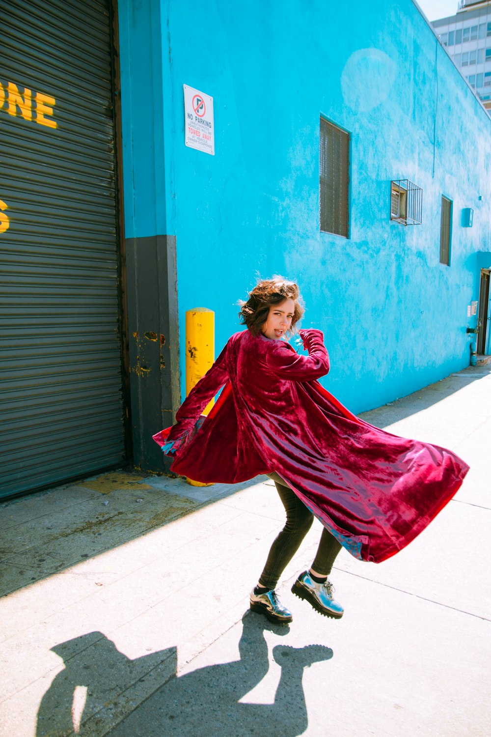 woman in red dress standing near blue wall