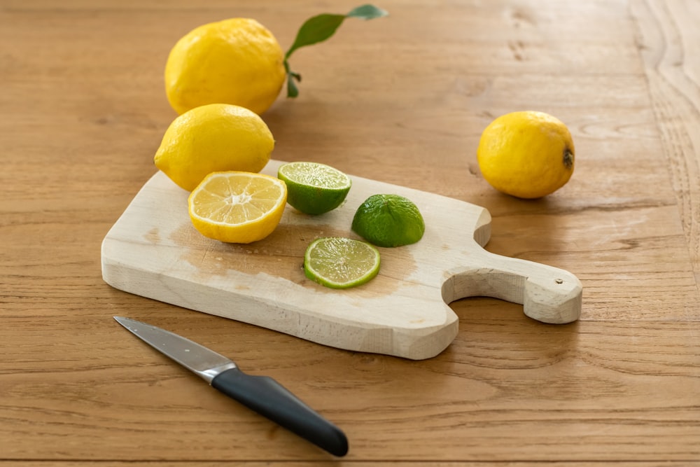 limão fatiado ao lado da faca na tábua de cortar madeira marrom