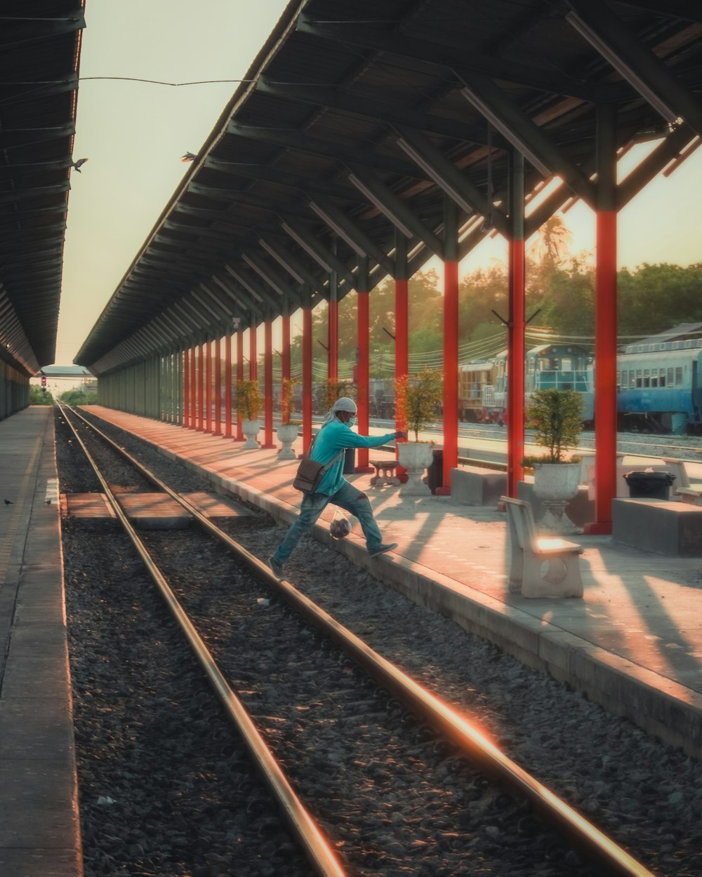 man in blue jacket and blue denim jeans walking on train rail during daytime