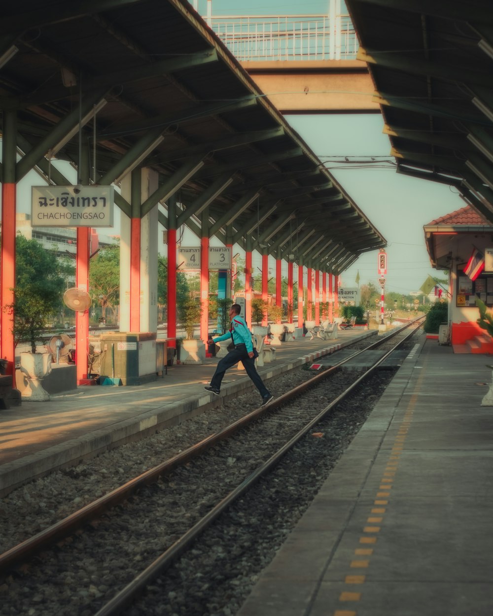man in blue jacket and black pants walking on train rail during daytime