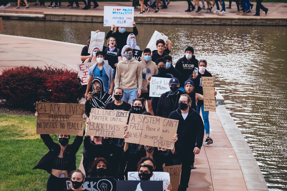 people holding signage standing on sidewalk during daytime