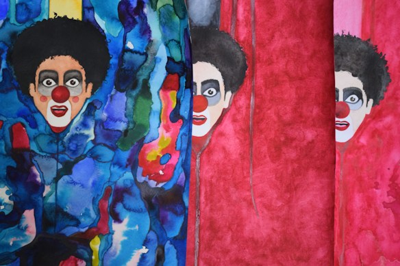 The image features a vibrant and abstract painting of clowns with exaggerated makeup and big red noses. The background is composed of swirling patterns in deep blues and reds, with some areas of green and yellow. The clowns are accentuated by stark black hair and facial features, creating a bold contrast against the colorful backdrop.