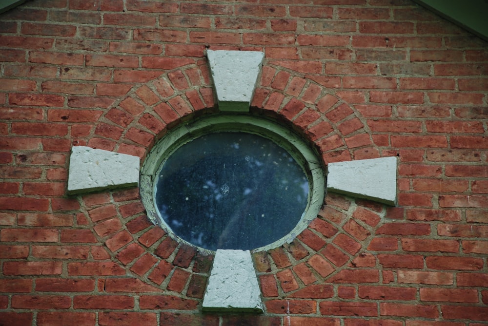 round mirror on brown brick wall