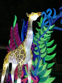 Gina la giraffa con il collo lungo decorato da luci e fiocchi colorati.