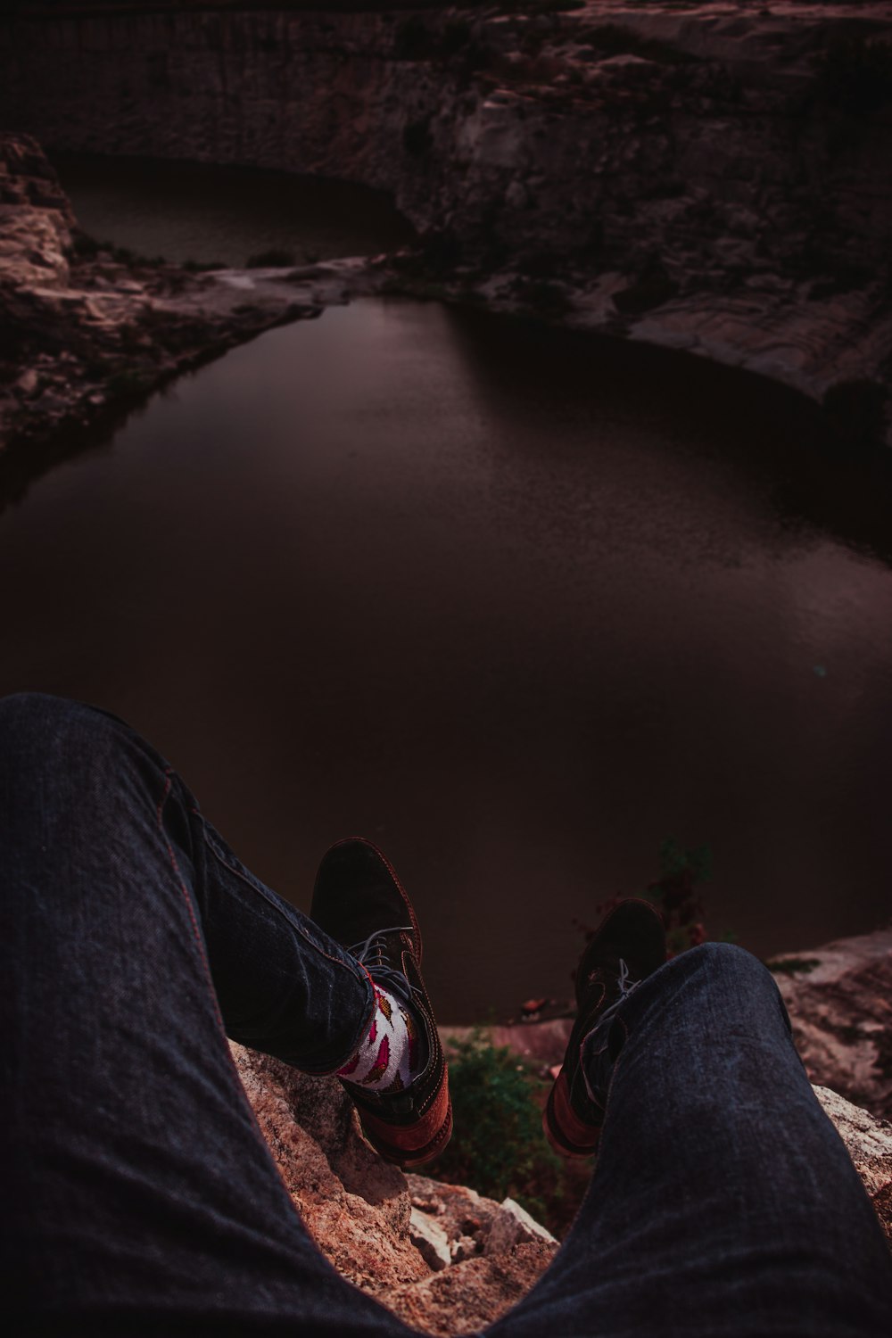 person in blue denim jeans and red sneakers sitting on rock