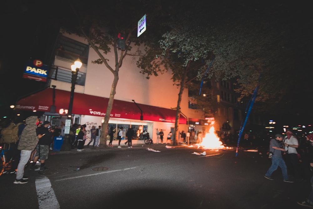 people walking on sidewalk near trees and buildings during night time