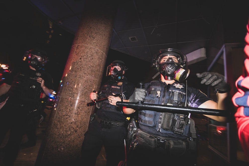 man in black jacket and helmet holding black rifle