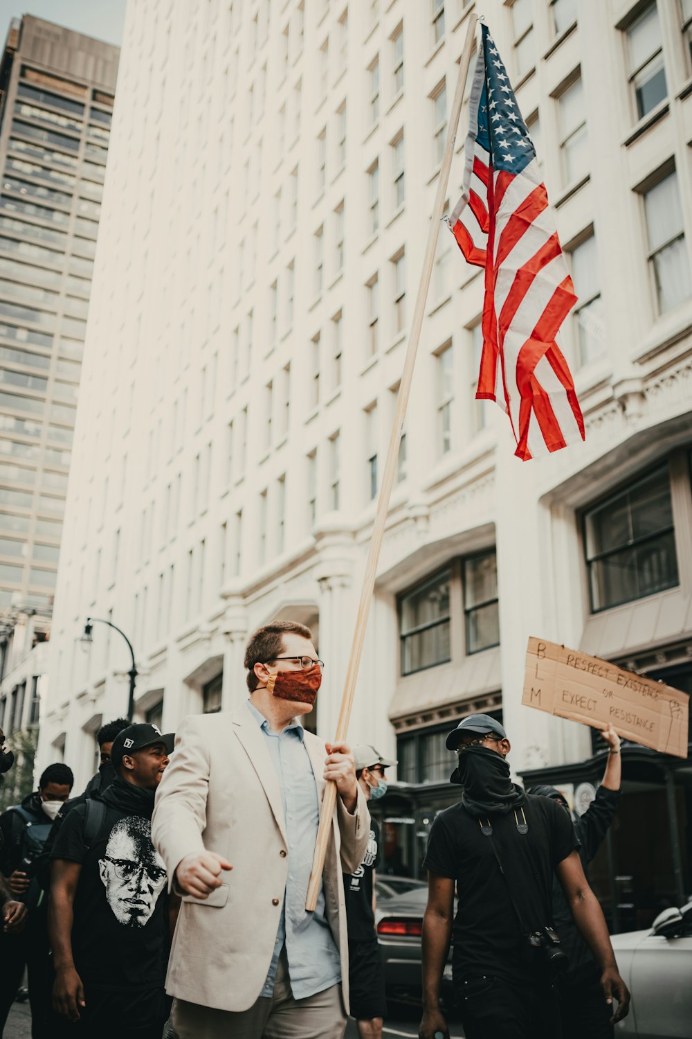 man in white dress shirt holding us a flag