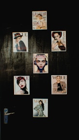A collection of magazine covers is displayed on a dark wall, each featuring a different portrait of a person. The covers are from well-known fashion magazines such as Vogue, Grazia, and Elle. The arrangement is aesthetically pleasing and suggests a focus on fashion and style.