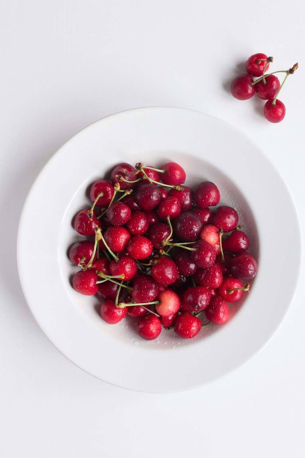 red cherries on white ceramic plate