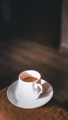 A warm coffee cup on a black and white table with subtle orange and light green accents.
