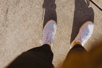 A pair of stylish sneakers resting on a concrete ledge with sunlight casting shadows.