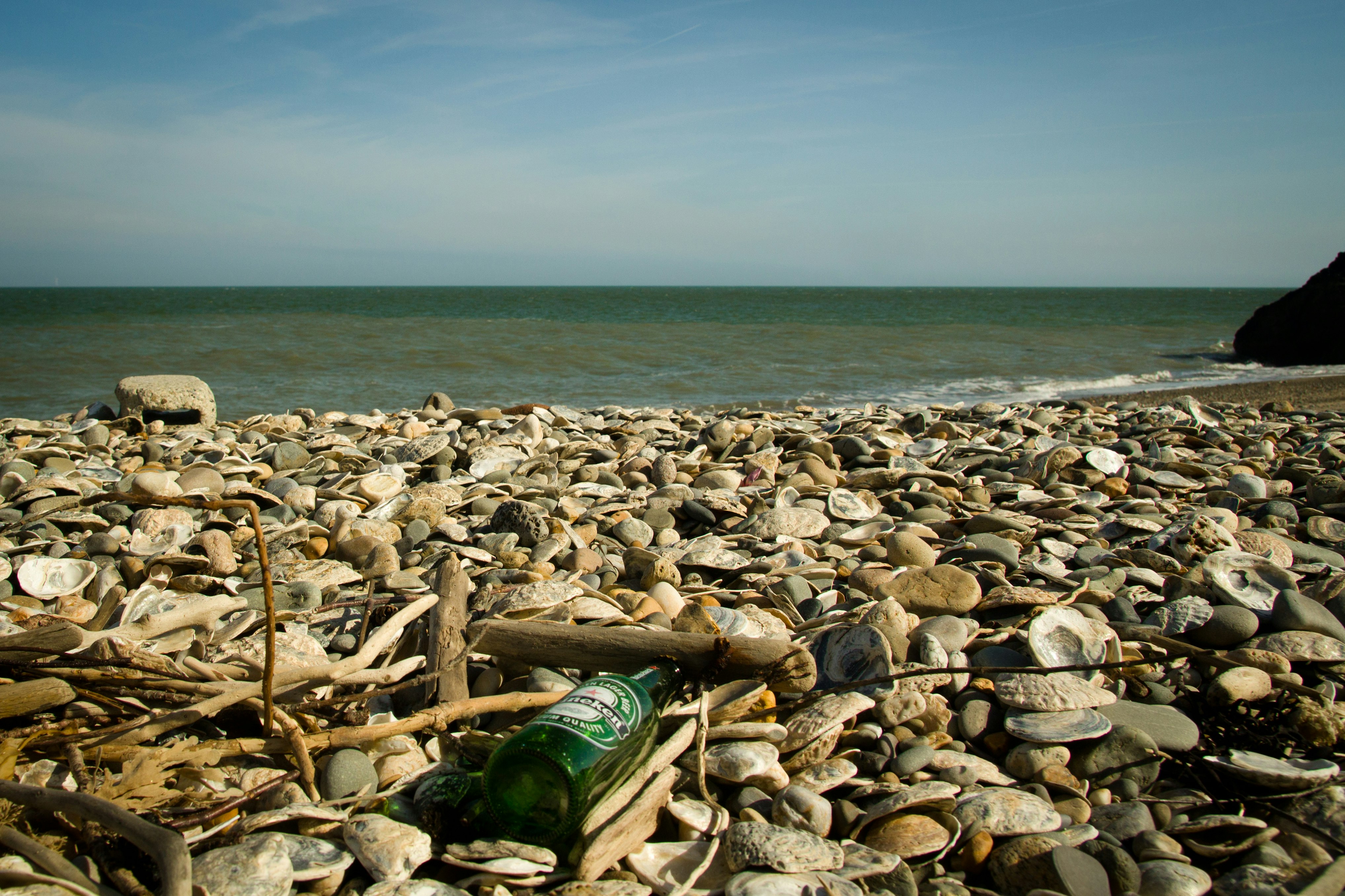 green glass bottle on brown and gray rocks near sea during daytime