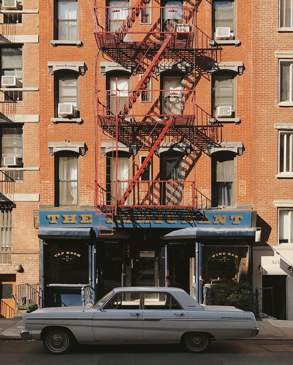 white and blue car parked beside brown building