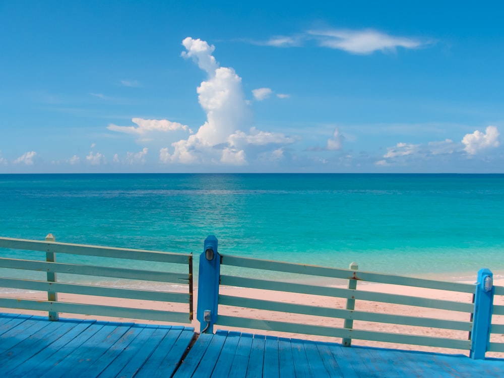 Weißes Holzdock am blauen Meer unter blauem und weißem bewölktem Himmel tagsüber