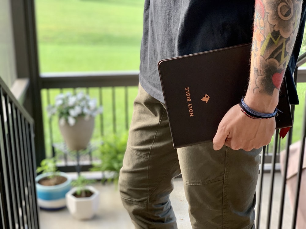 person in brown pants holding black book