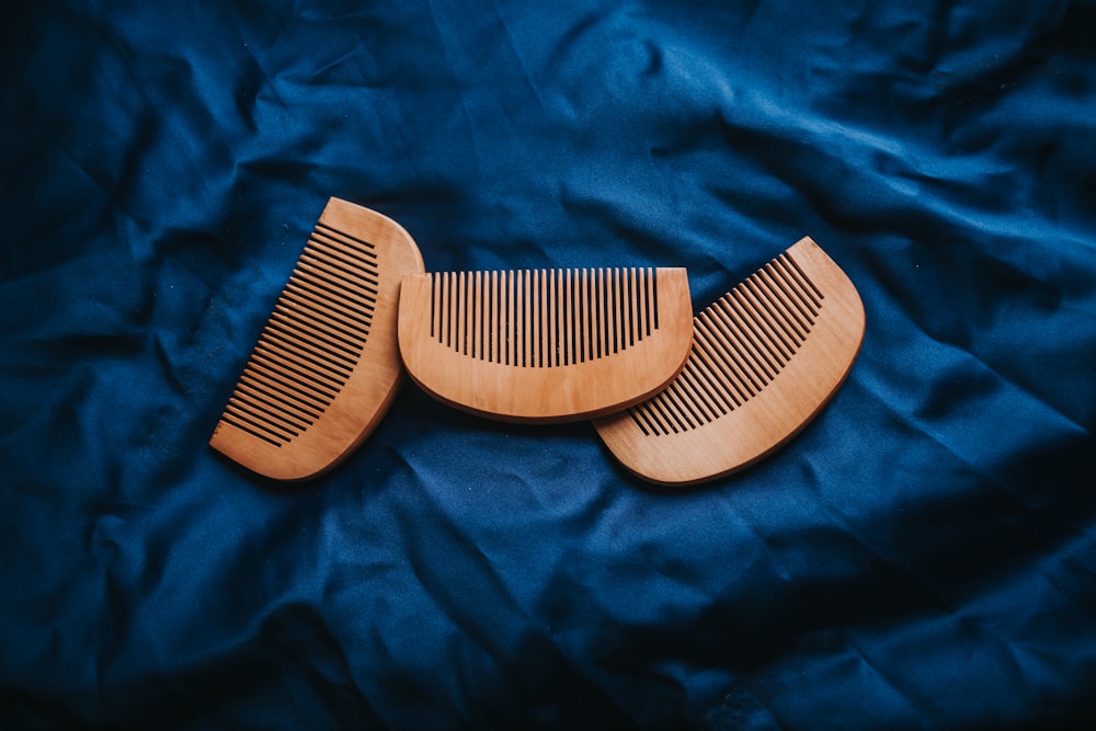 a couple of wooden combs sitting on top of a blue cloth