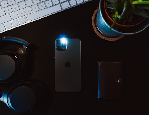 Flat lay of an iPhone surrounded by everyday items, showcasing the FlashGlow app ready to brighten any moment.