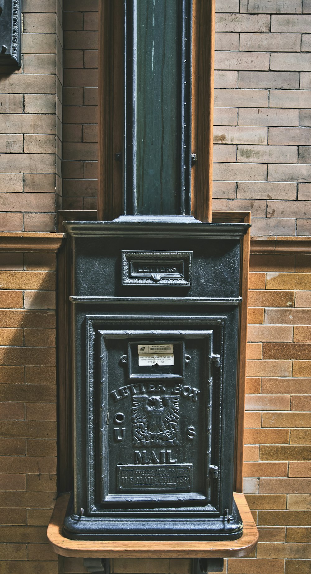 black metal mail box mounted on brown brick wall