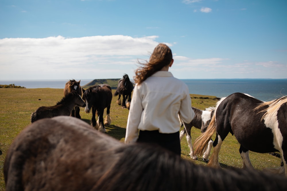 woman in white long sleeve shirt standing beside black horse during daytime