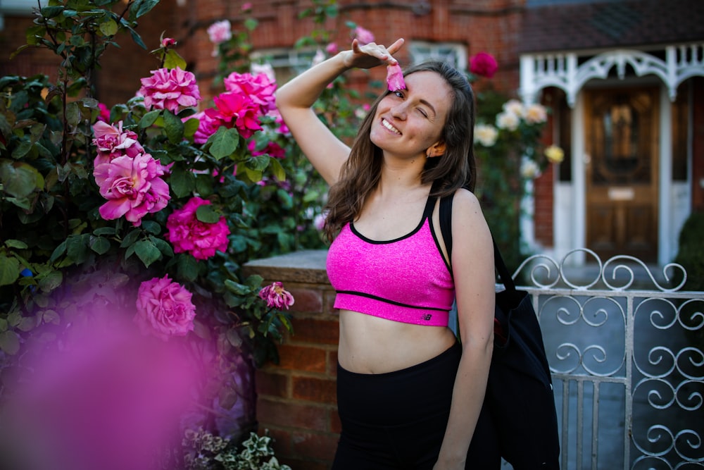 woman in black tank top and black skirt standing beside pink flowers