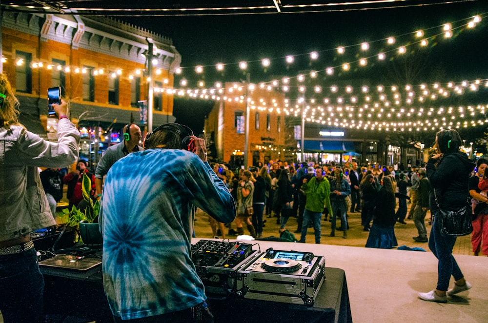 man in blue and white long sleeve shirt standing in front of people during nighttime