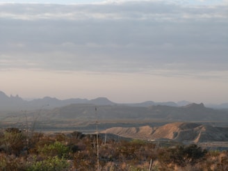 A minimalist landscape featuring rolling hills under a vast, cloudy sky.