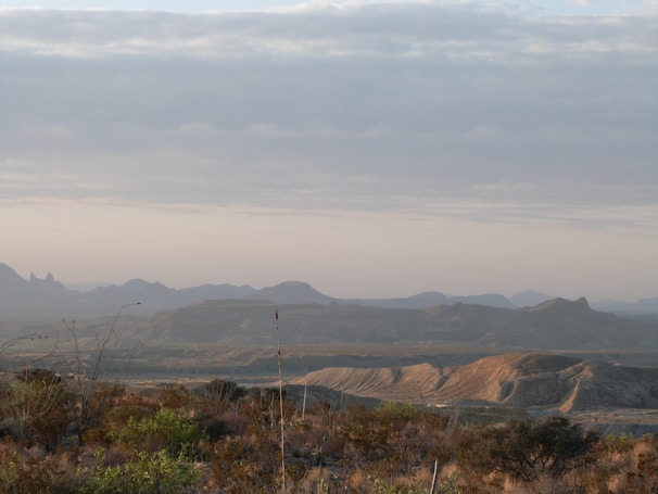 A minimalist landscape featuring rolling hills under a vast, cloudy sky.