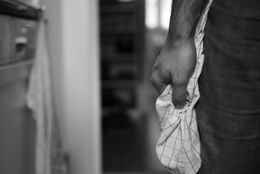 foto in scala di grigi di una persona che tiene in mano un tessuto