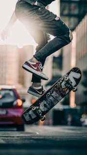 person in black pants and black and white sneakers jumping on skateboard