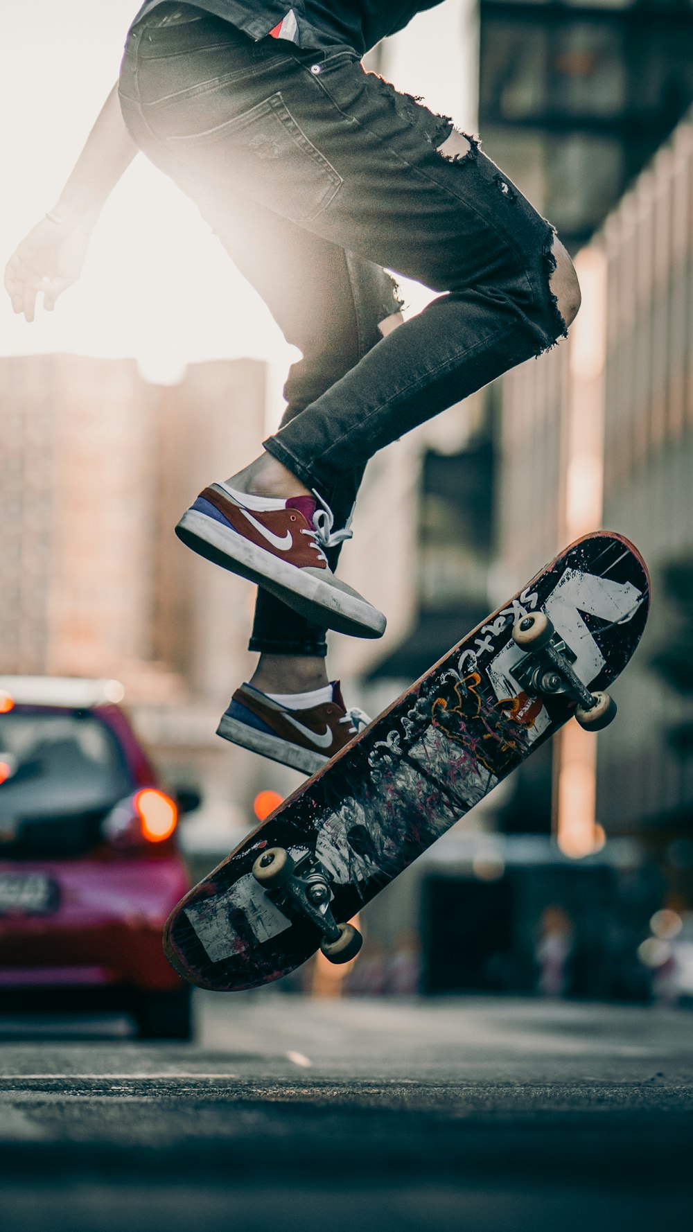 personne en pantalon noir et baskets noires et blanches sautant sur une planche à roulettes