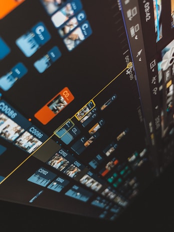 A close-up view of a video editing timeline on a computer screen with multiple video clips and tracks. Blue and orange clips are organized in a diagonal layout, and various icons and controls are visible on the interface.