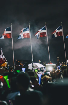 A vibrant crowd dressed in Liberia's red, white, and blue celebrating outdoors with flags waving under a bright summer sky in Houston.