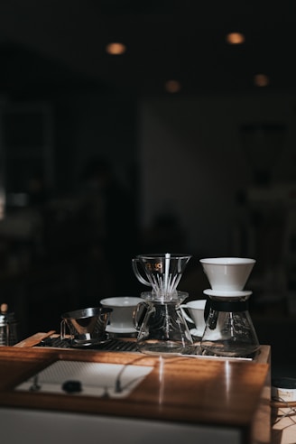 A warm, inviting photo of various coffee brewers arranged on a rustic wooden table.