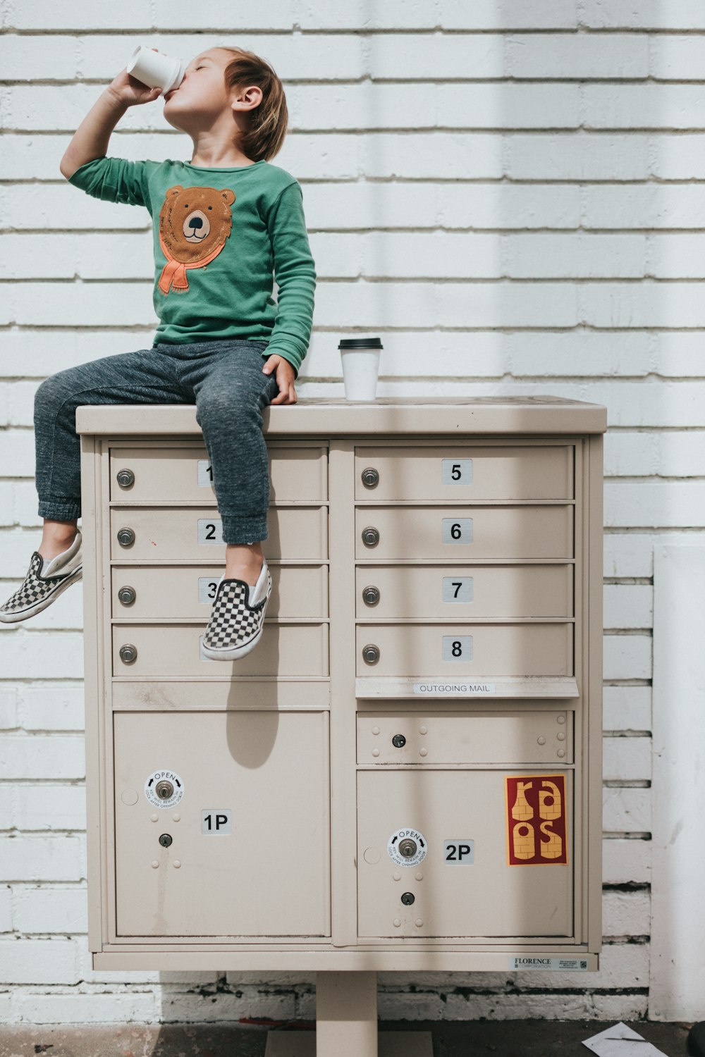 boy in green hoodie and blue denim jeans sitting on gray steel cabinet