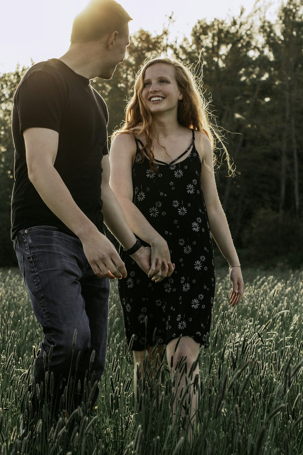 woman in black and white floral tank top and blue denim jeans standing on green grass