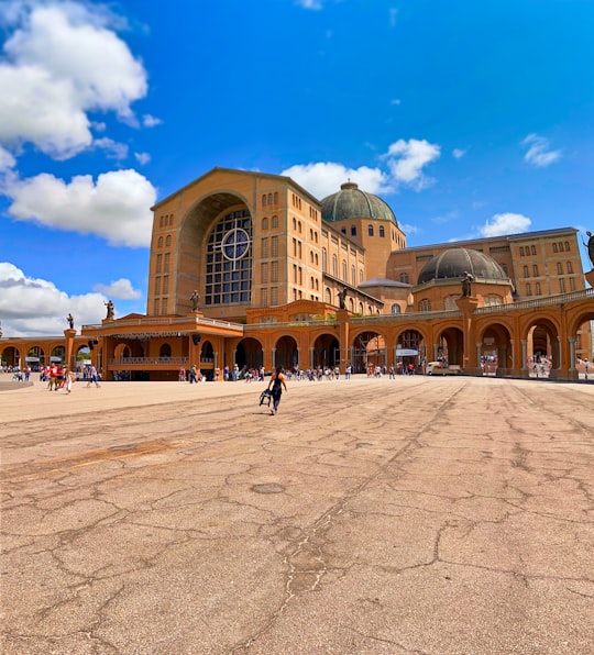 people walking on street near brown concrete building during daytime in Basilica of the National Shrine of Our Lady of Aparecida Brasil