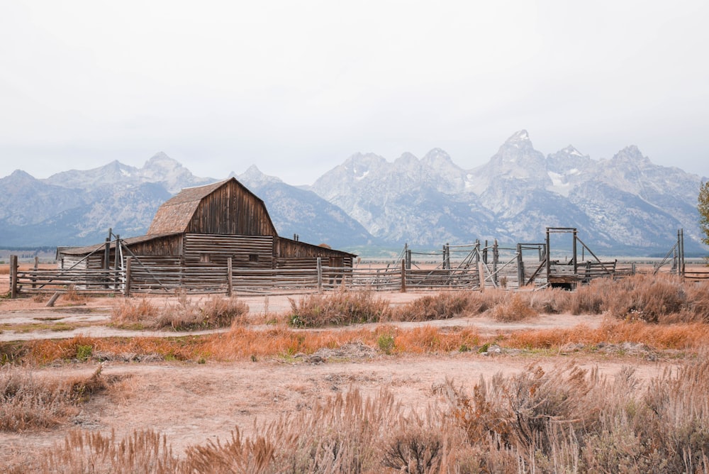 brown wooden house on brown grass field near mountains during daytime