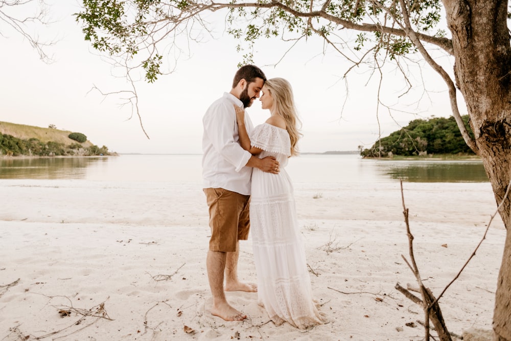 uomo e donna che si baciano sulla spiaggia durante il giorno