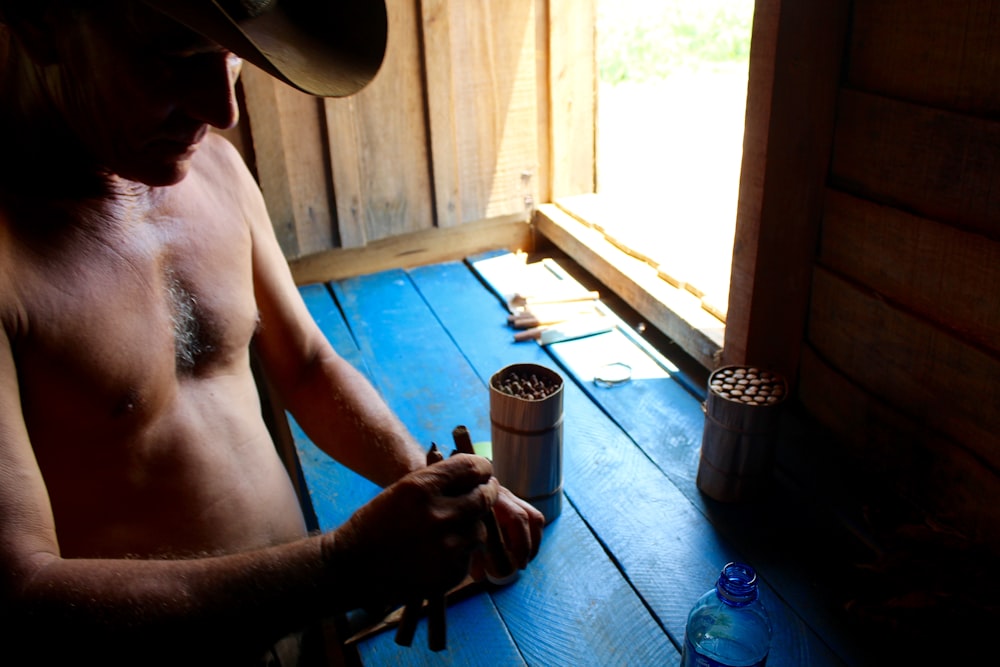 Homme au chapeau de cowboy marron assis sur le sol bleu photo