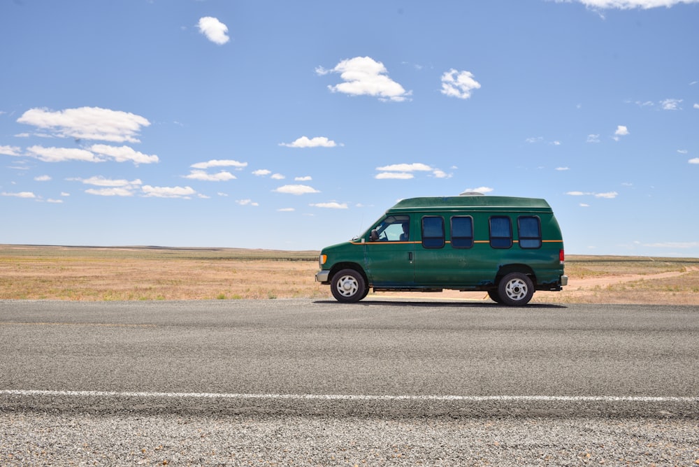 green suv on gray asphalt road under blue and white sunny cloudy sky during daytime