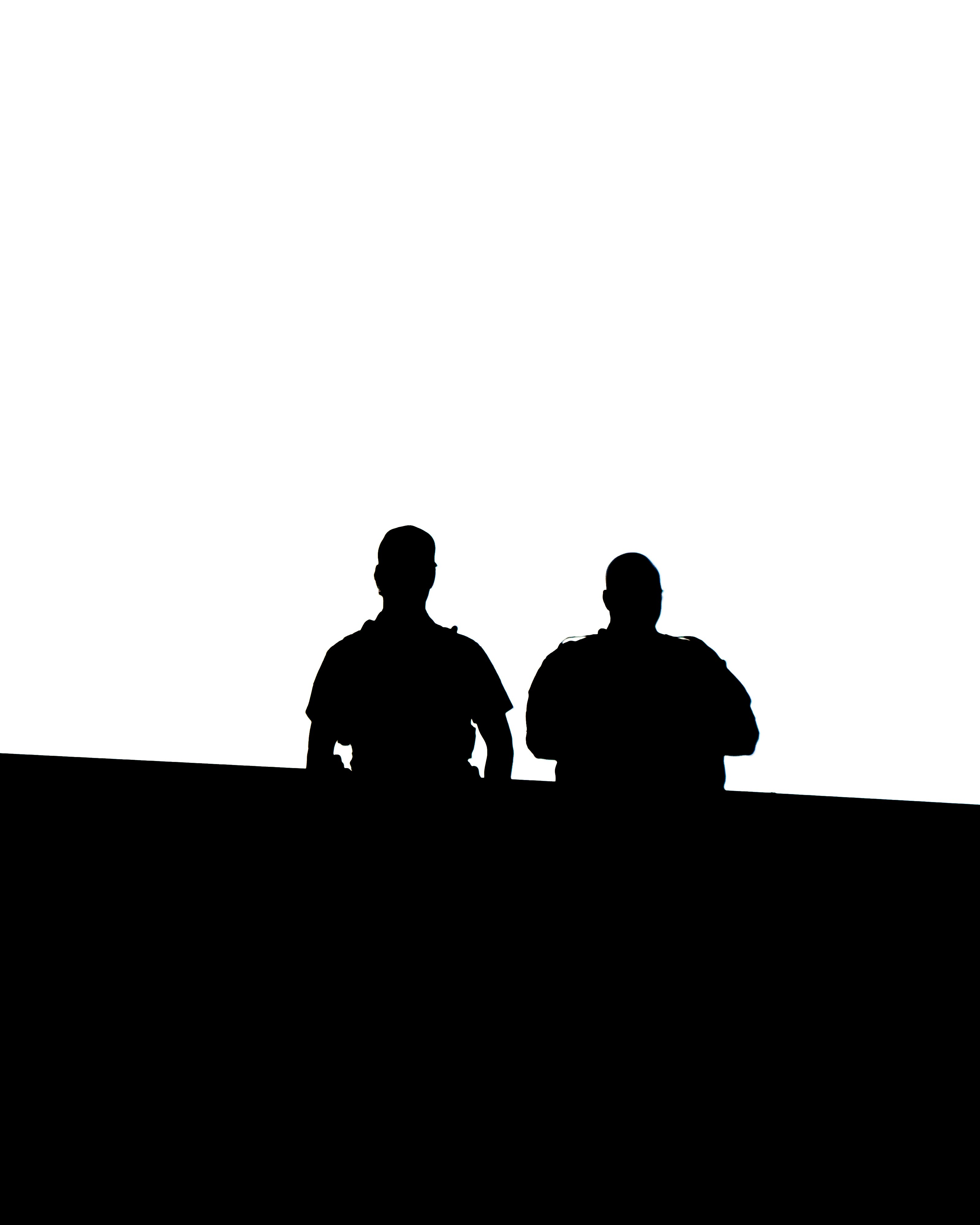 silhouette of 2 men standing on the ground