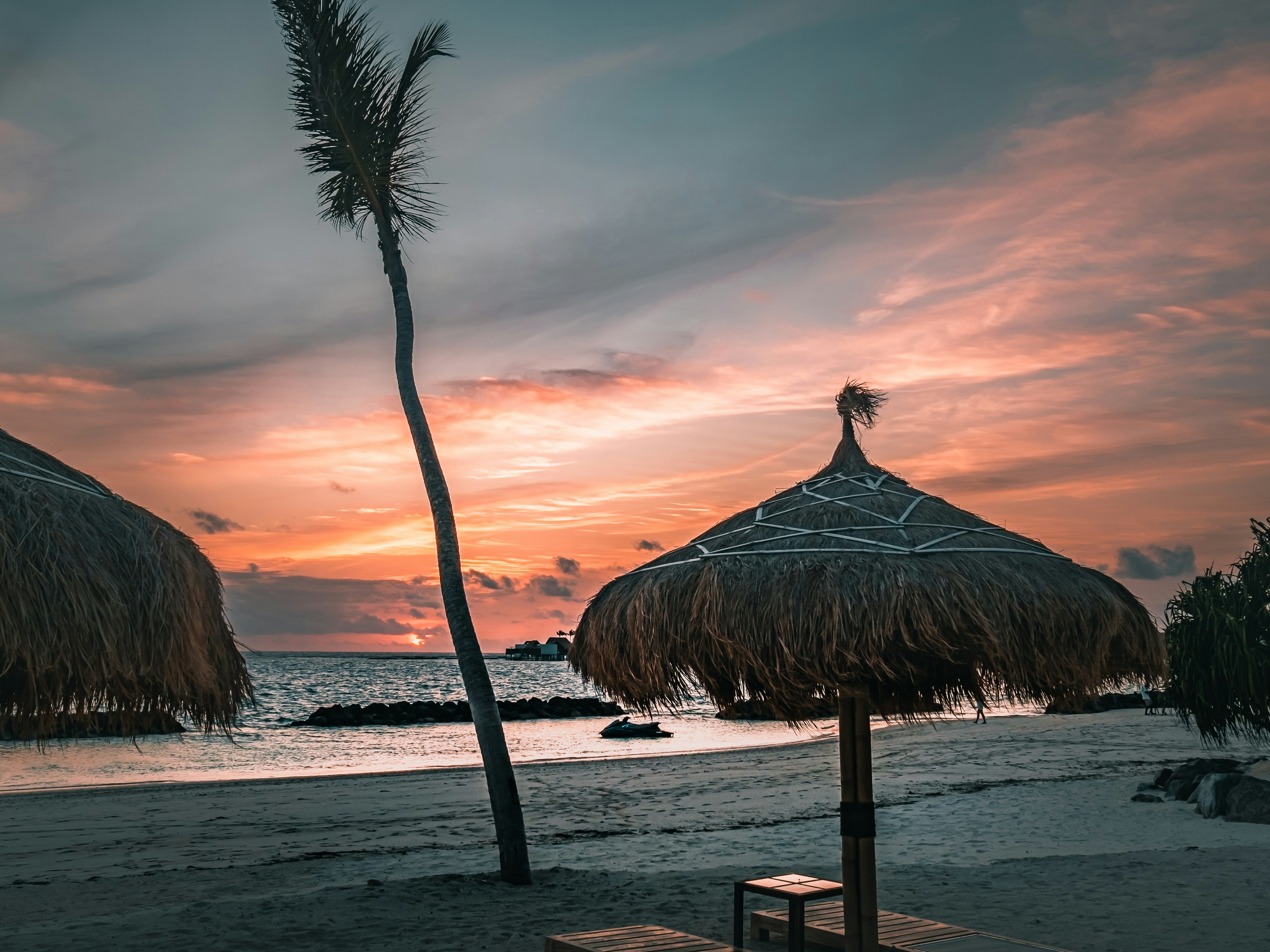 brown nipa hut on beach during sunset