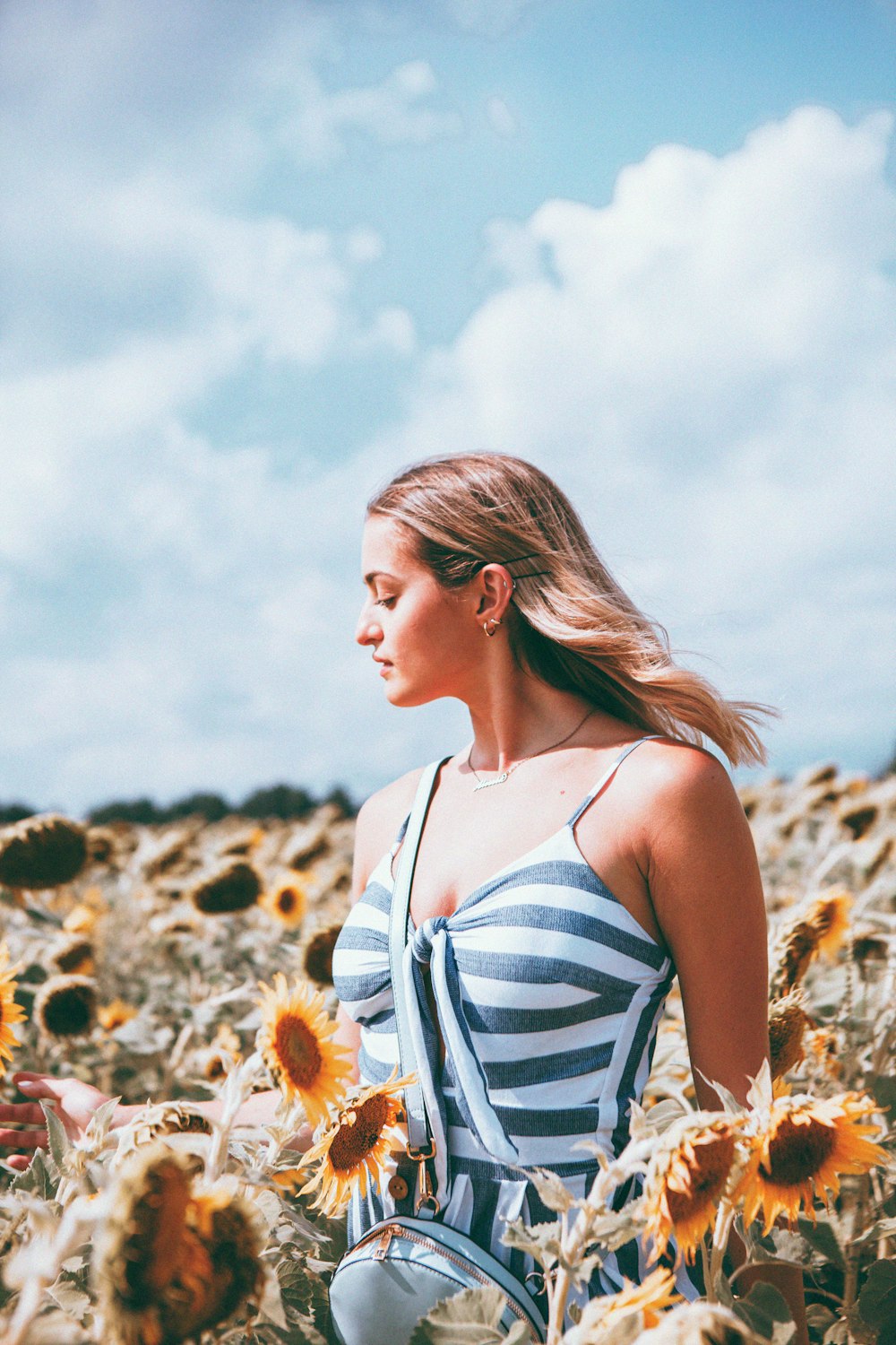 woman in white and blue stripe tank top standing on brown field during daytime