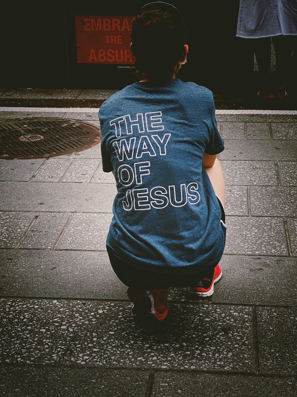 woman in blue and white crew neck t-shirt and black pants standing on gray concrete