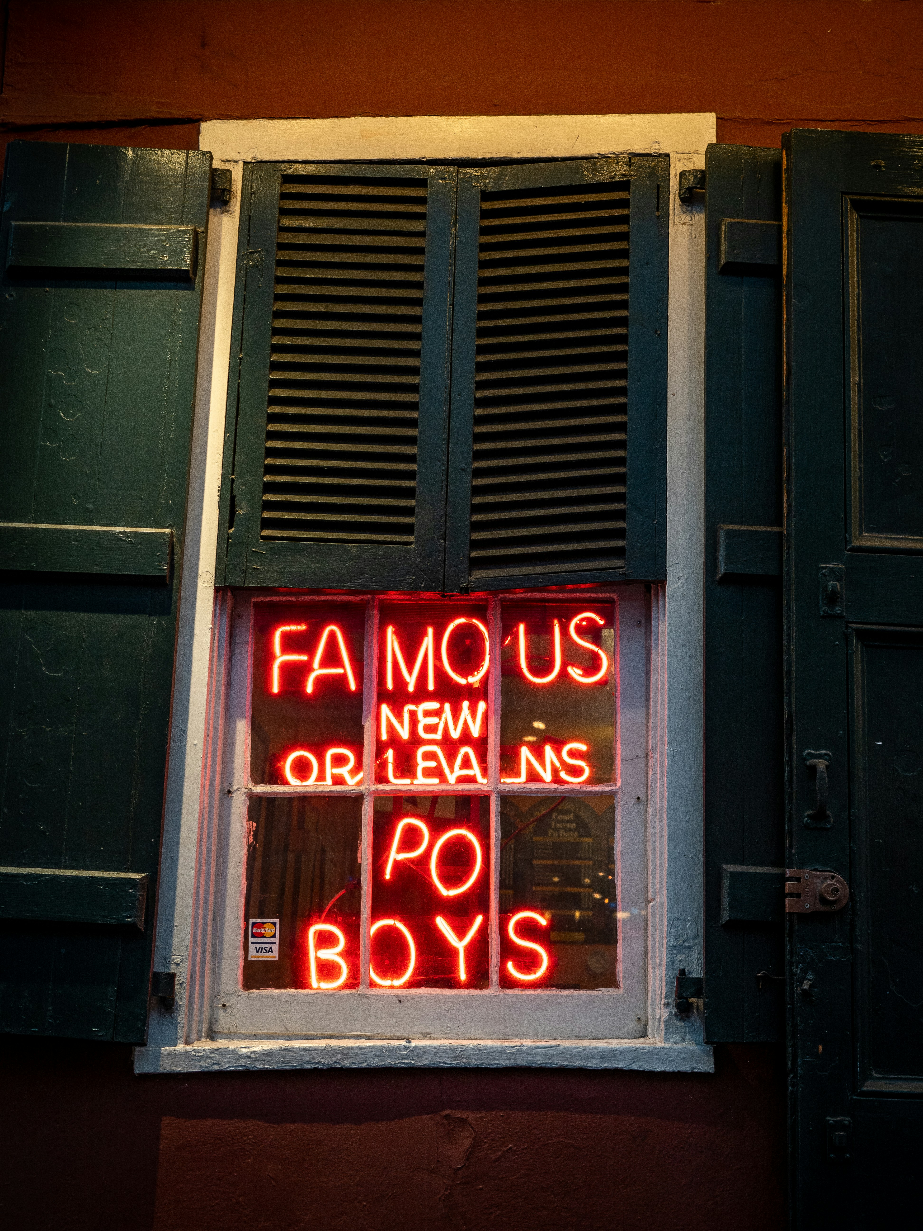 Window with shutters and neon Famous New Orleans Po Boys sign