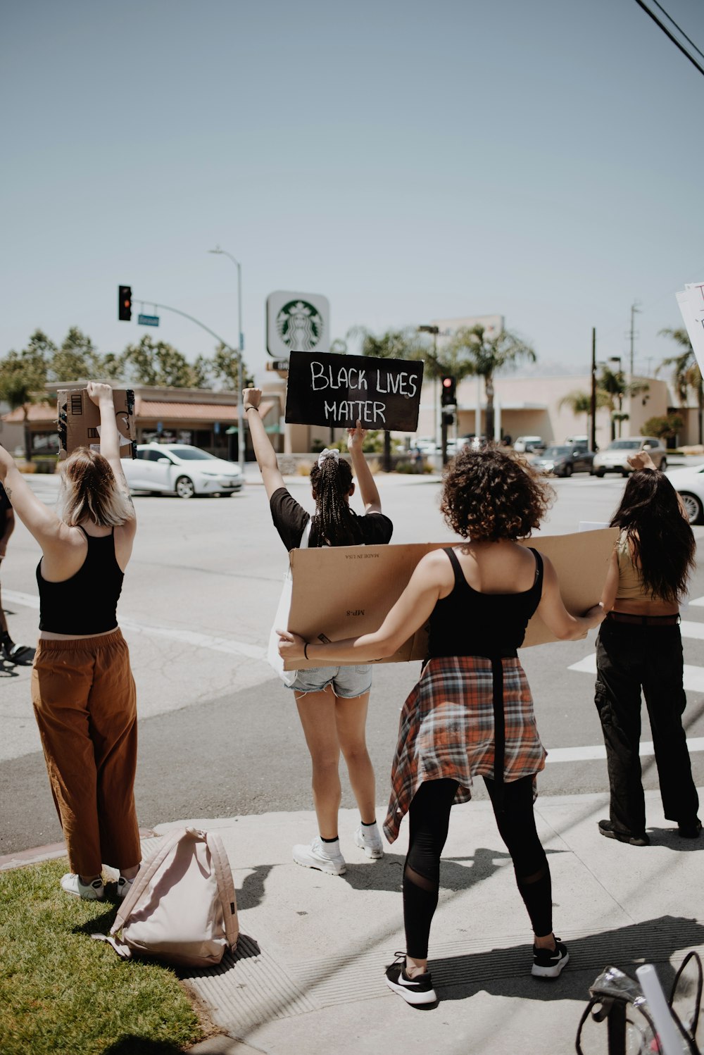 woman in black tank top and red white plaid skirt walking on street during daytime